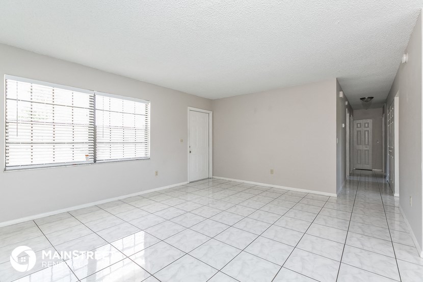 an empty living room with a large window and a tiled floor