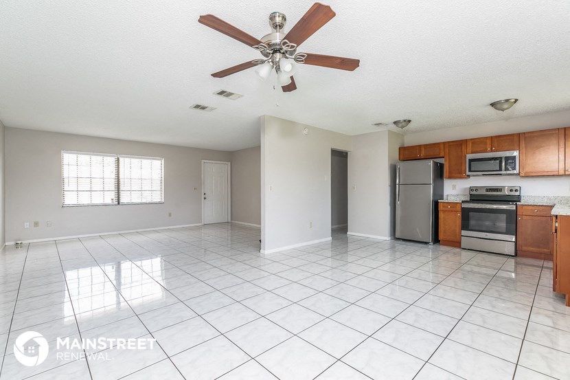an empty kitchen with a ceiling fan and white tiles