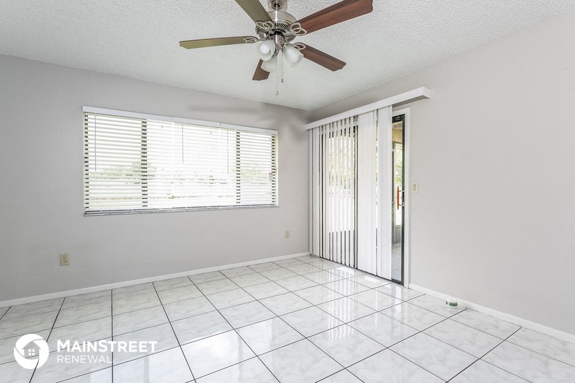 an empty living room with a ceiling fan and a sliding glass door