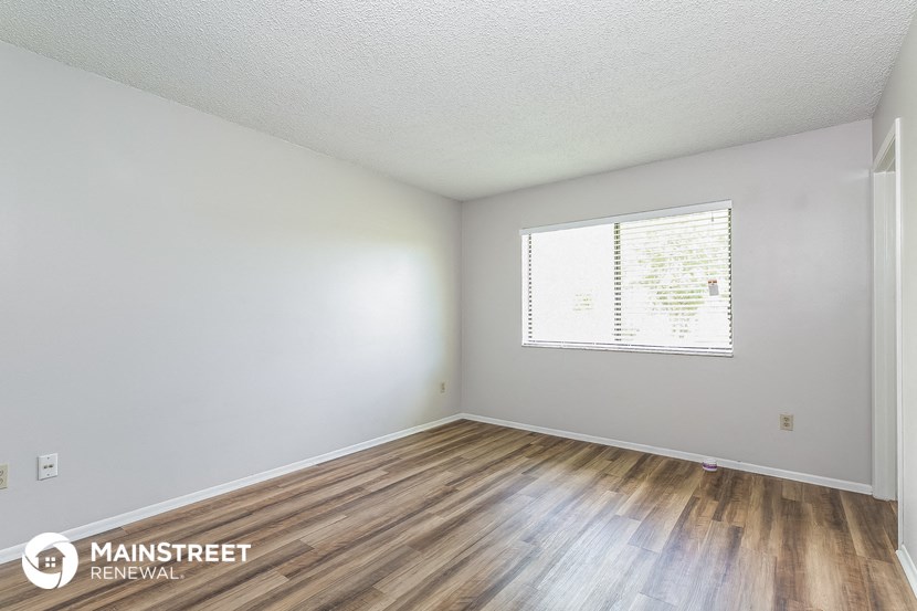 the spacious living room with wood flooring and white walls