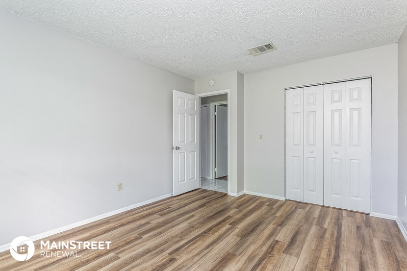 the living room of an apartment with wood flooring and white walls