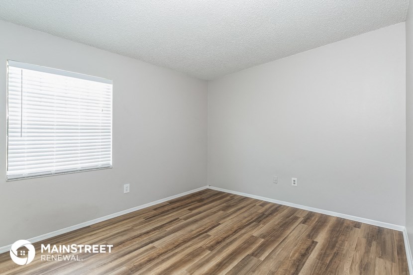 a bedroom with wood flooring and white walls and a window