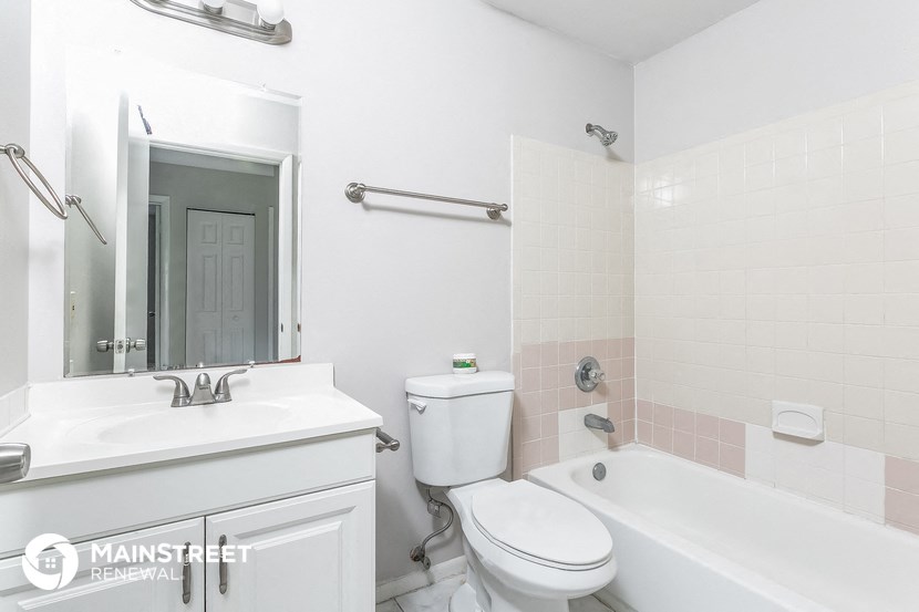 a white bathroom with a toilet sink and tub and a mirror