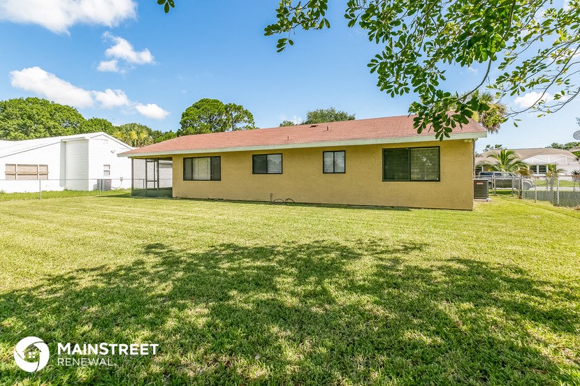 a small yellow house with a grass yard and a fence