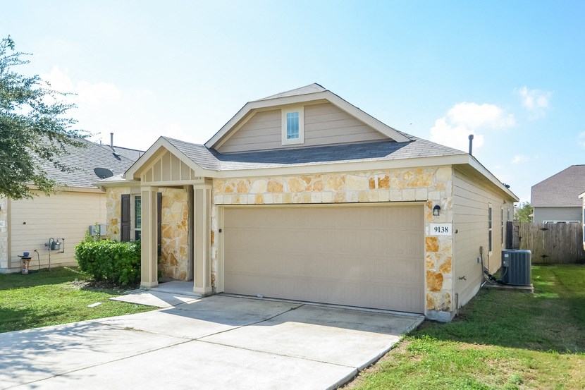 a tan house with a garage door and a driveway