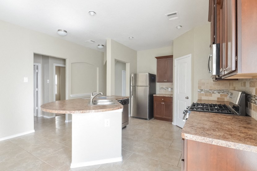 a kitchen with an island and a stainless steel refrigerator