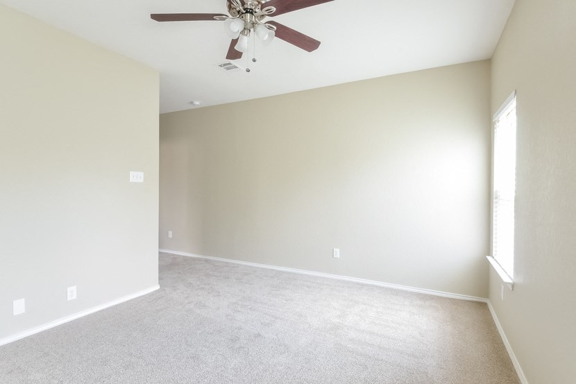 an empty living room with a ceiling fan
