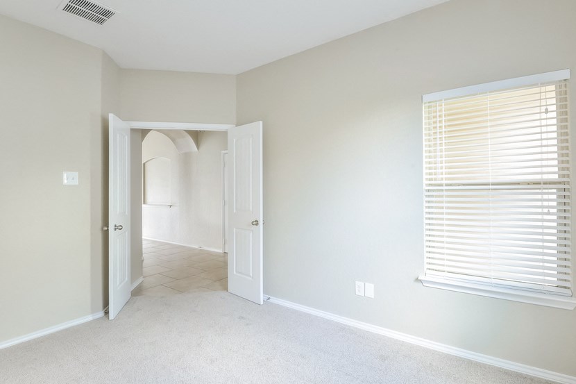 an empty room with a door to a hallway and a window