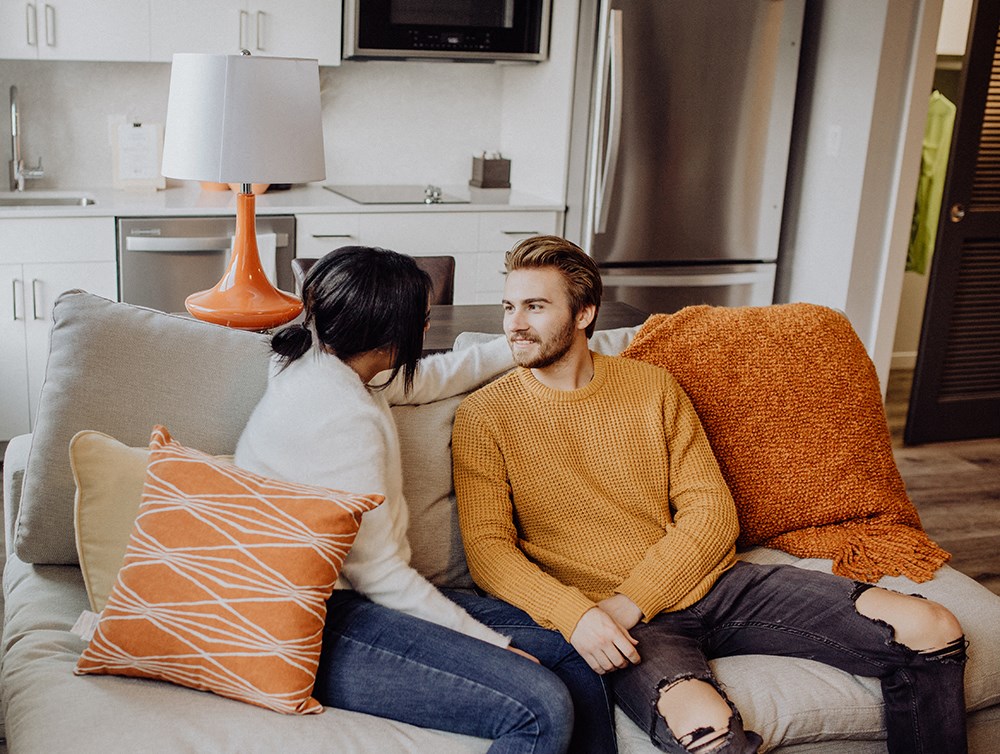 a man and woman sitting on a couch with pillows
