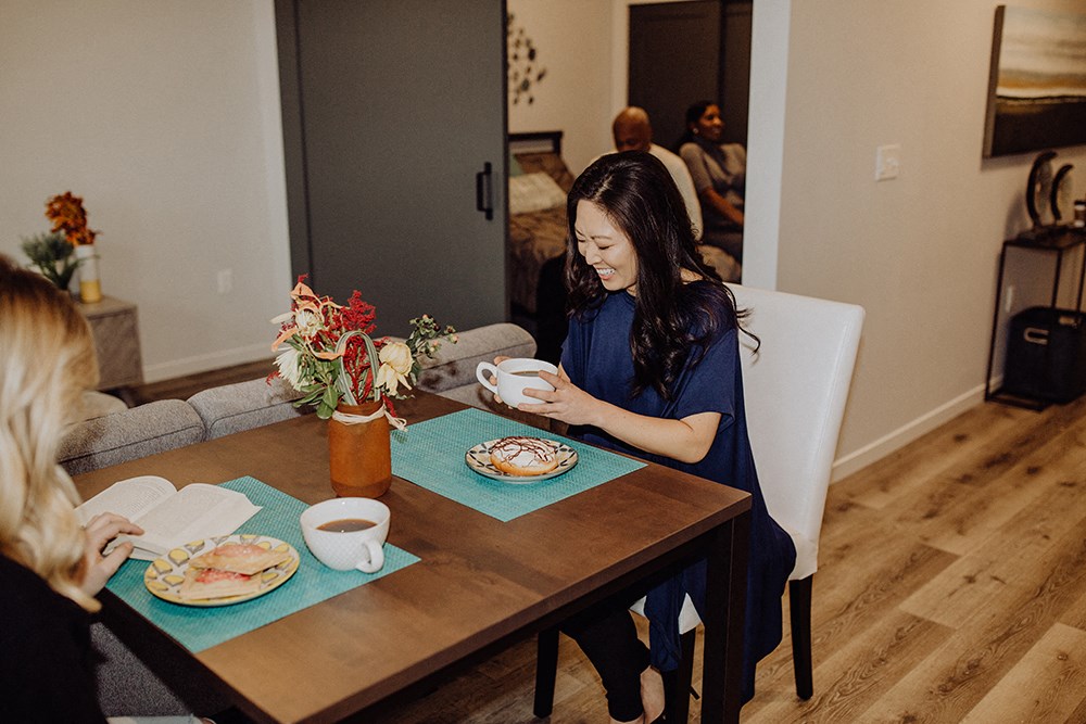 a woman sitting at a table drinking coffee and reading a book