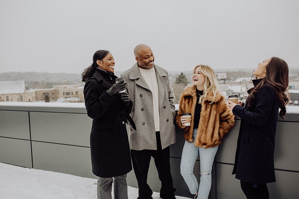 a group of people standing on a roof talking and laughing