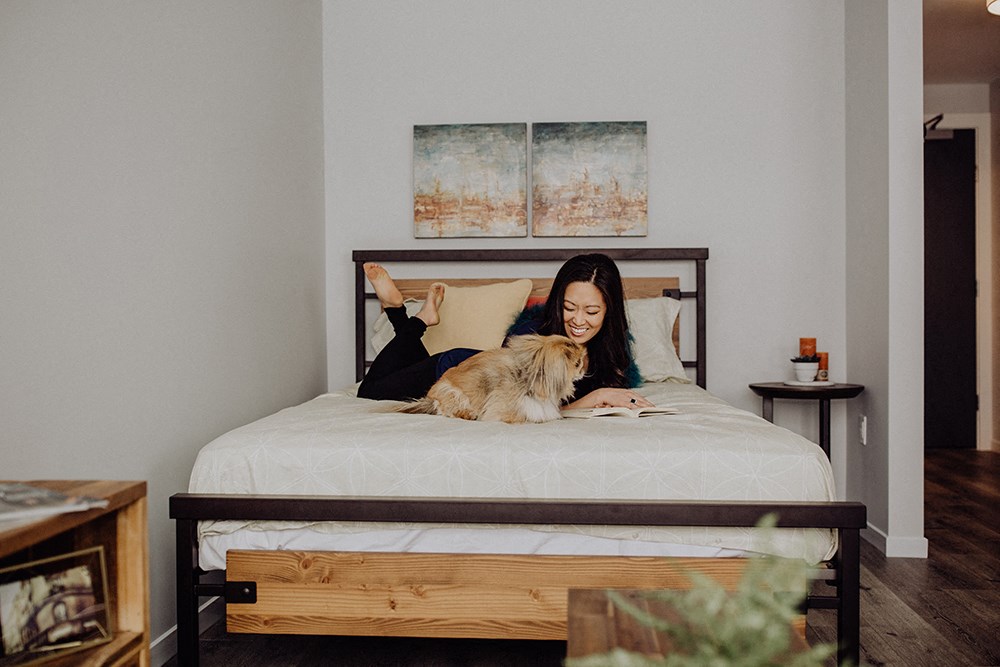 a woman laying on a bed with a dog