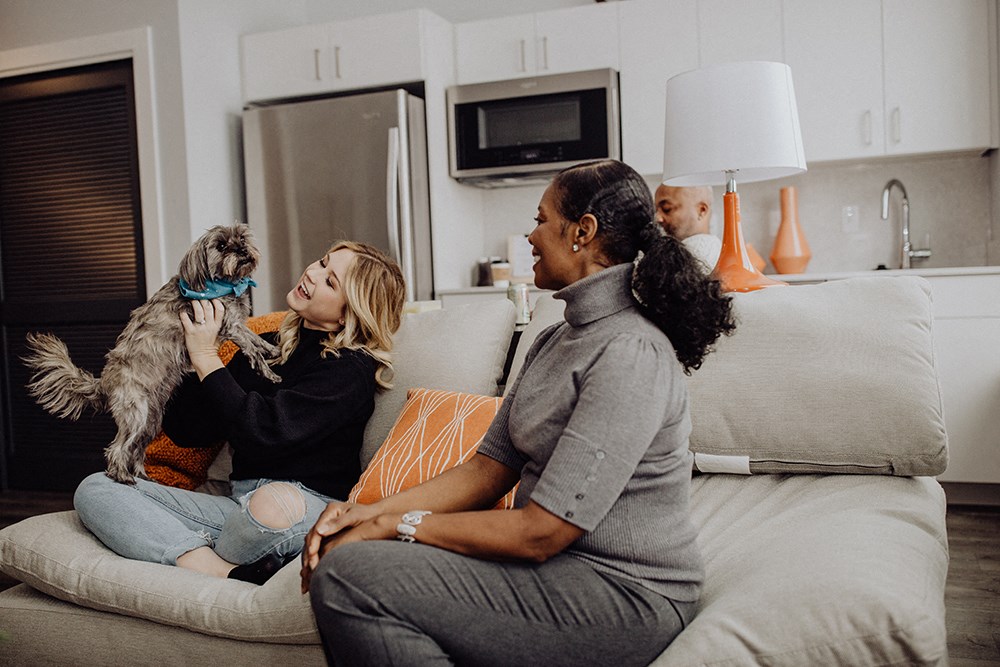 two women sitting on a couch with a dog