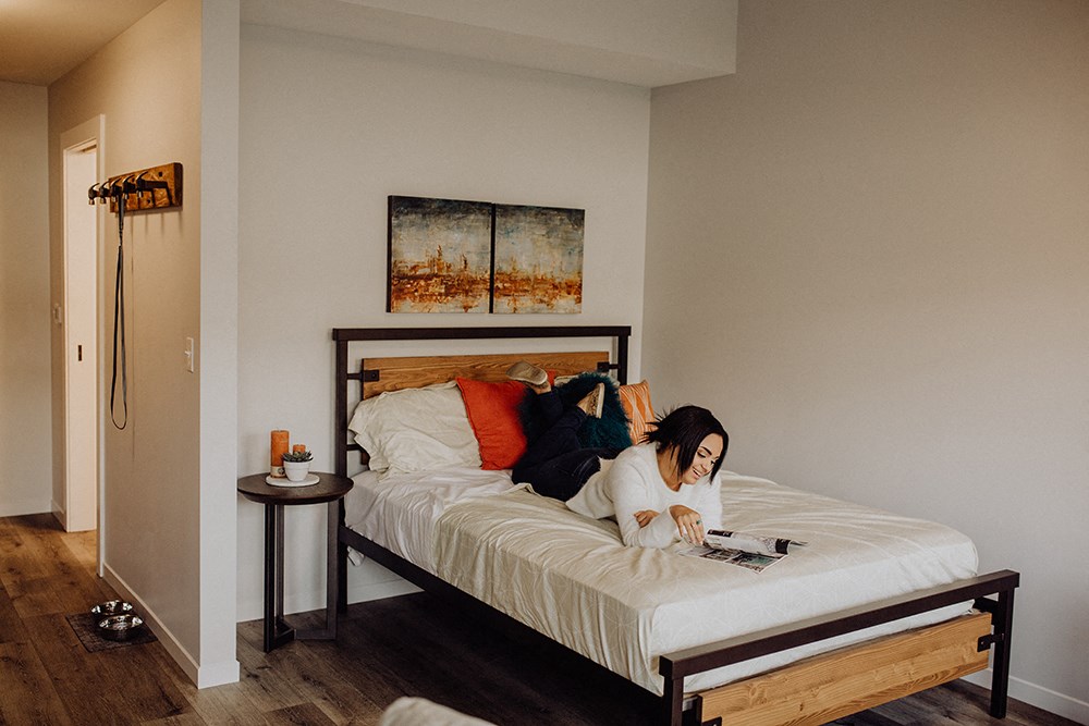 a woman laying on a bed reading a book in a bedroom