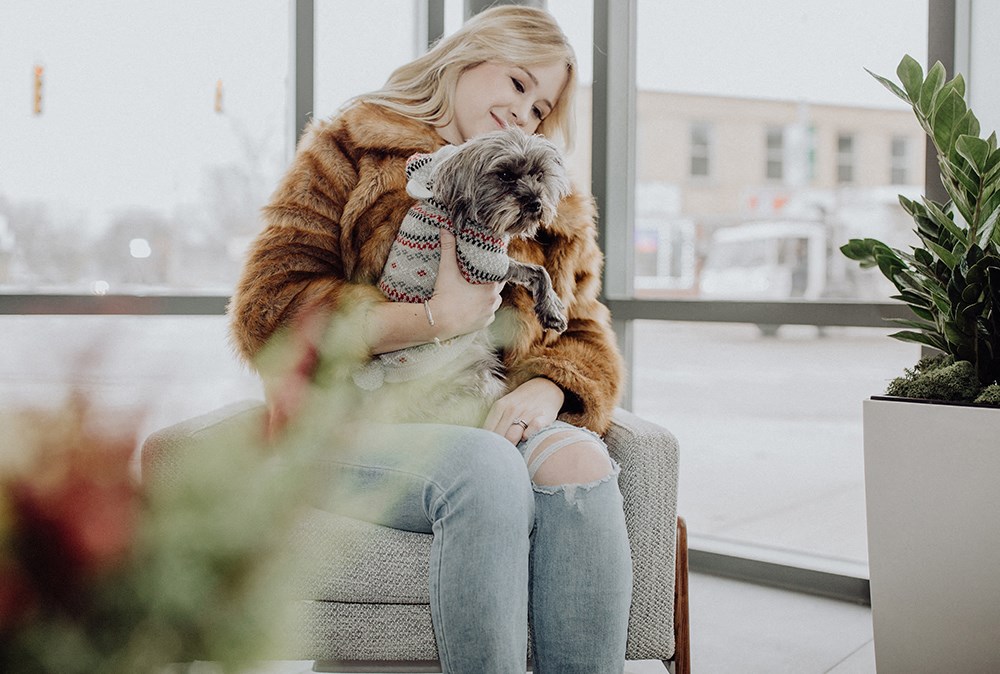 a woman sitting on a couch holding a dog