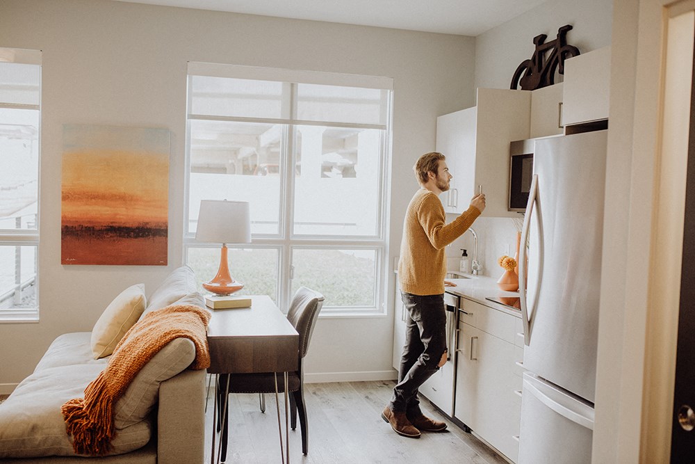 a man standing in a kitchen next to a refrigerator