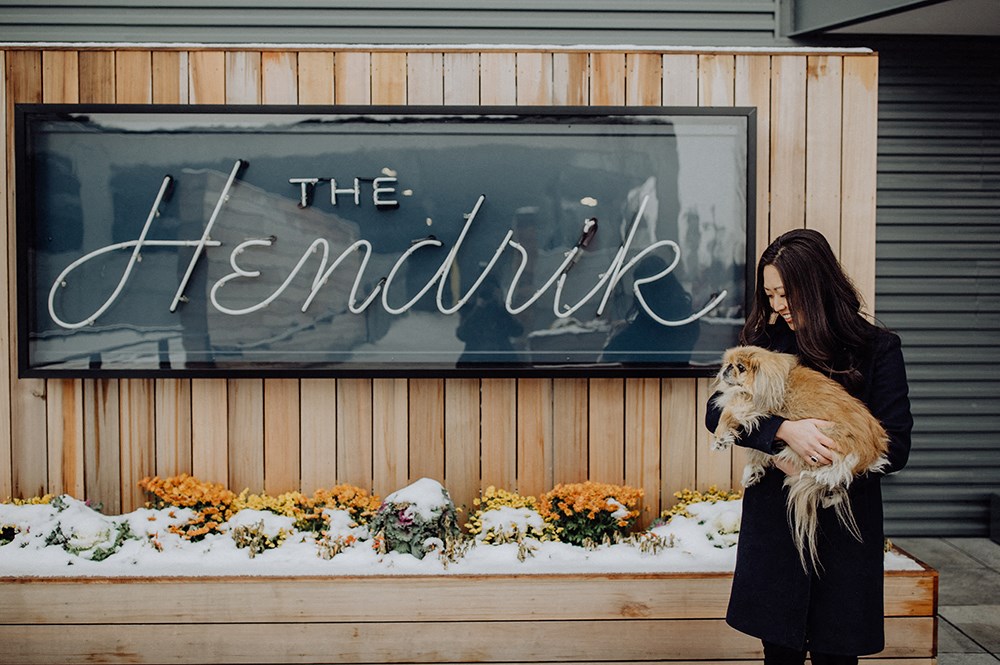 a woman holding a dog in front of a sign for the hendrikuter
