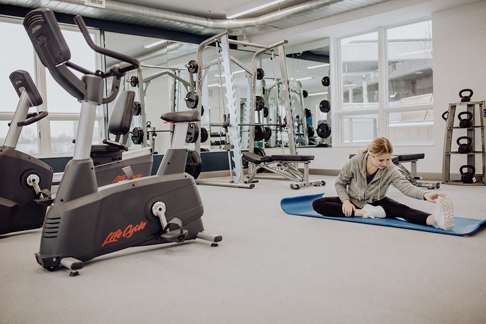 a woman sitting on the floor in a gym with weights