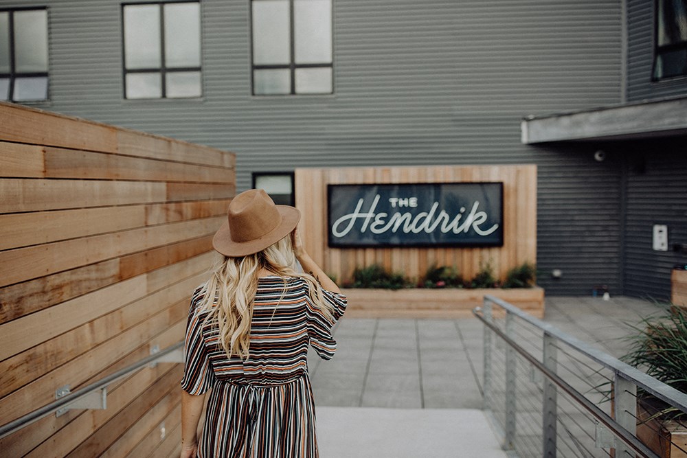 the back of a woman wearing a hat standing in front of a building
