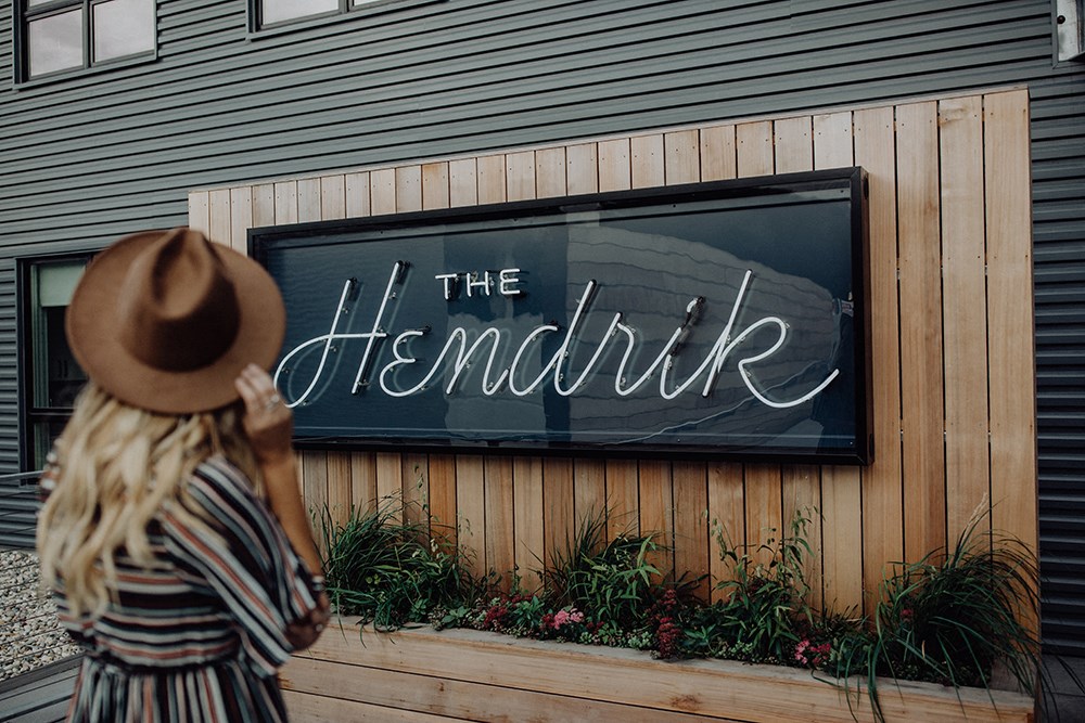 a woman wearing a hat looking at a sign on the side of a building