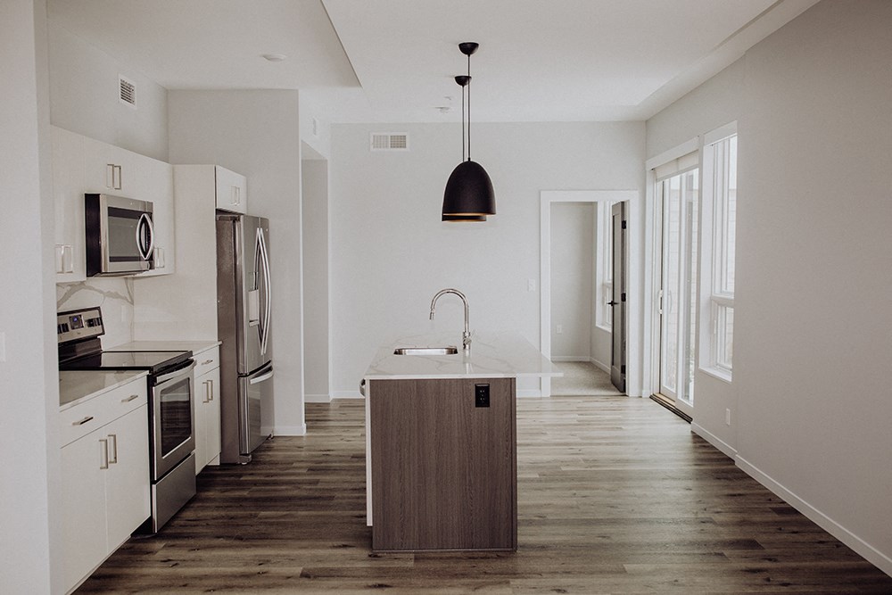 a kitchen with white cabinets and stainless steel appliances and a wooden floor