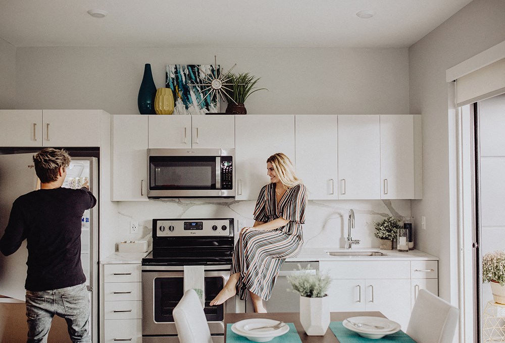 a man and a woman sitting on a kitchen counter