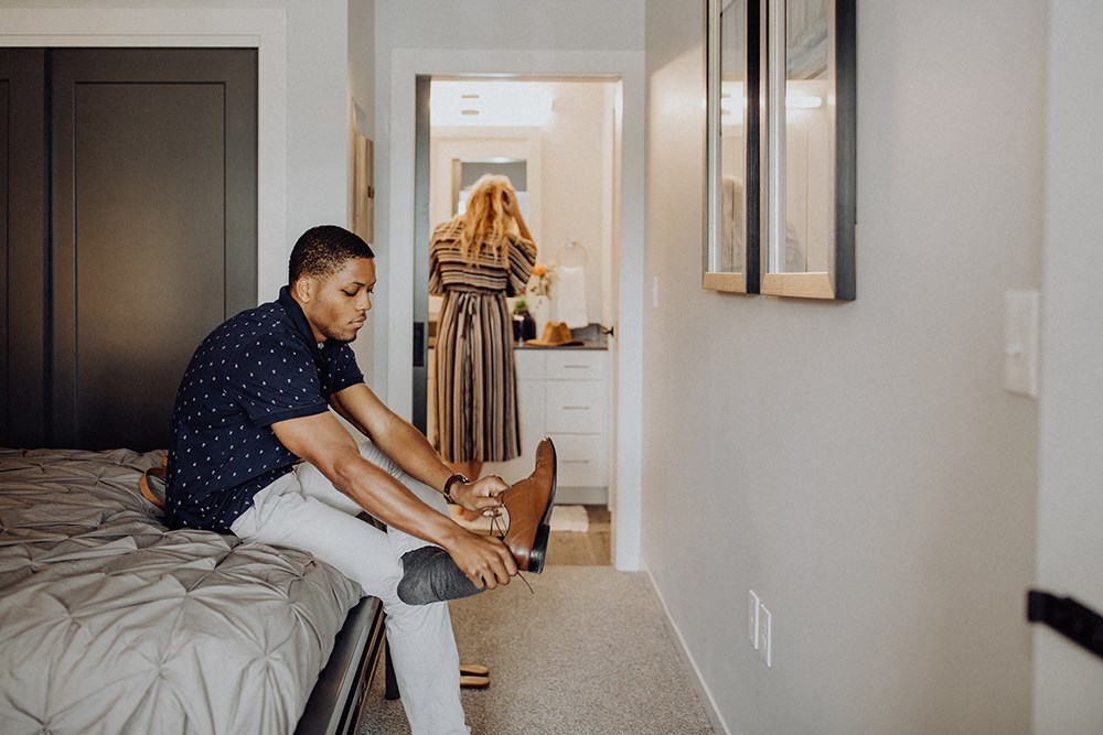 a man sitting on a bed putting on his shoes