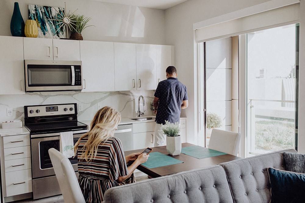 a woman sitting at a kitchen table looking at her cell phone while a man is
