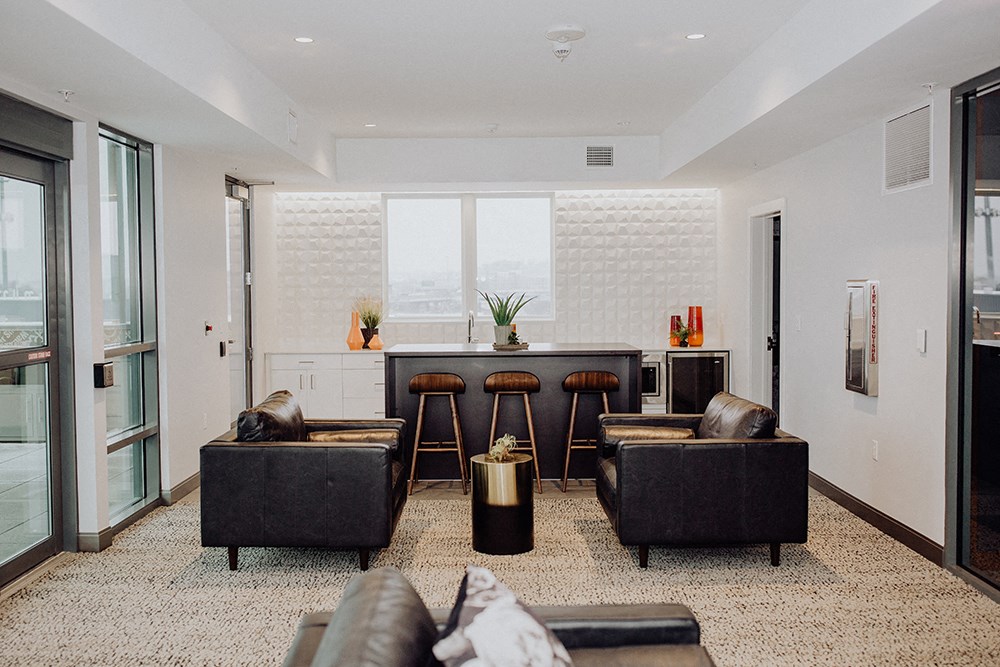 a living room with couches and a bar and a kitchen