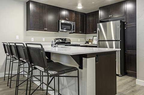 a kitchen with stainless steel appliances and a counter with bar stools