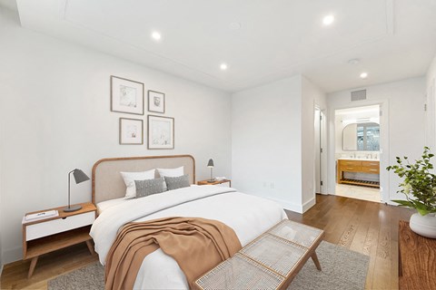 a bedroom with a large bed and white walls and wood floors