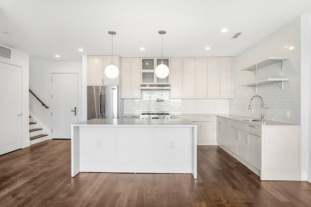 a large white kitchen with a large island in the middle