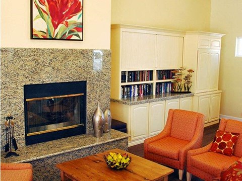 A living room with a fireplace, bookshelf, and two chairs.