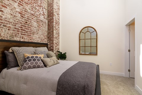 a bedroom with a bed and a brick wall