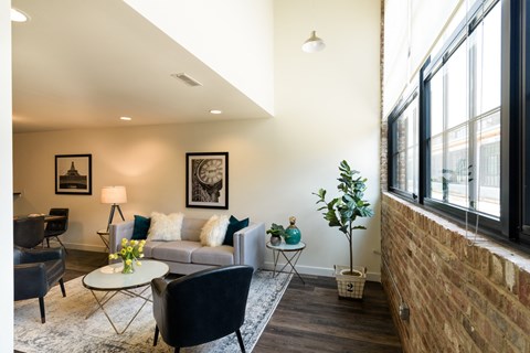 a living room with a couch and chairs and large windows