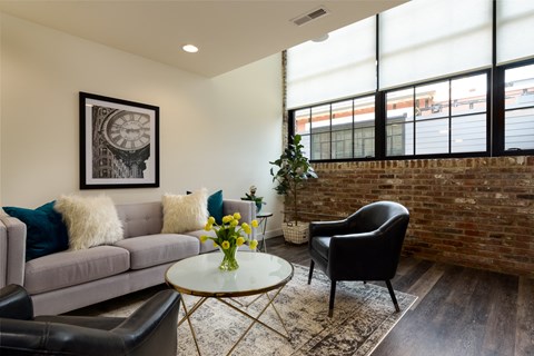 a living room with a couch and a table and a brick wall