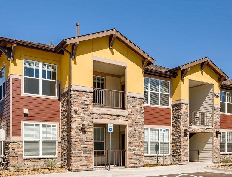 an apartment building with yellow and brown walls and a sidewalk