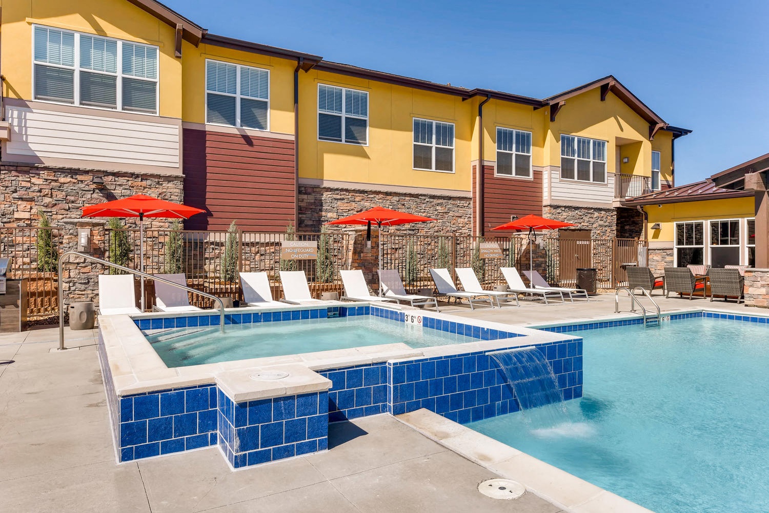 a swimming pool with chairs and umbrellas in front of a building
