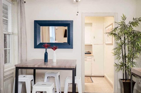 a dining room with a table and chairs under a blue mirror