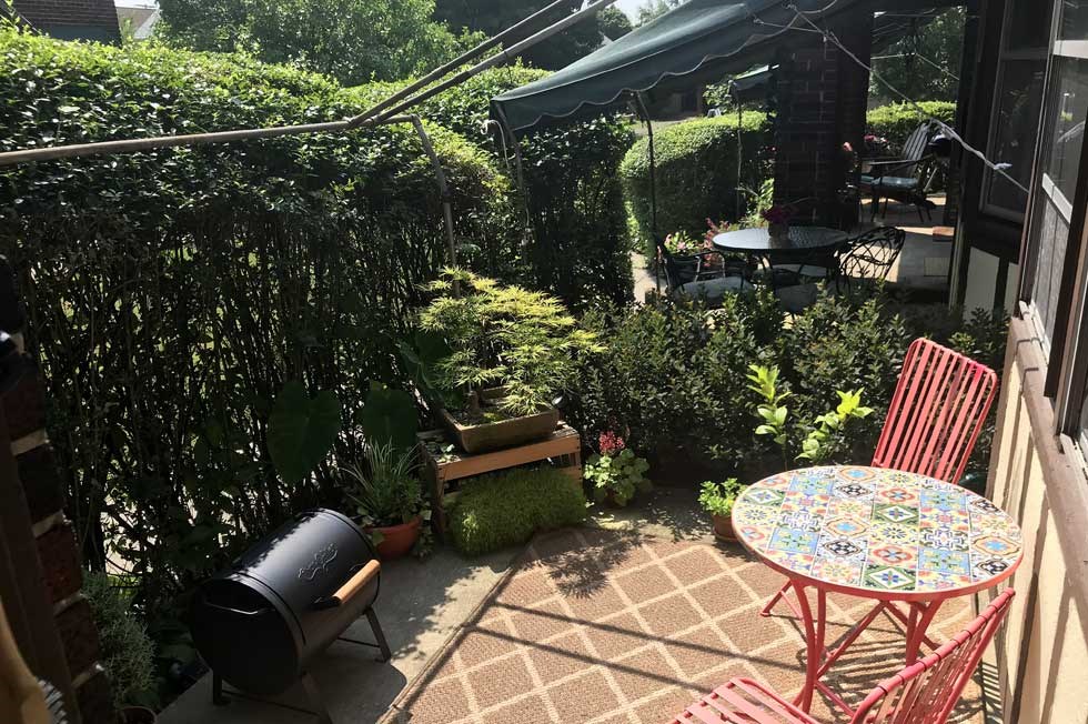 a patio with a table and chairs and a garden
