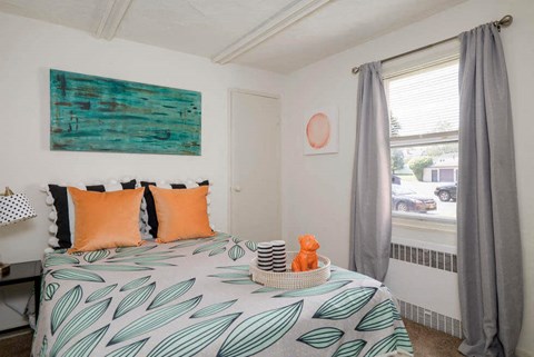 A bedroom with a bed covered in a leaf patterned bedspread.