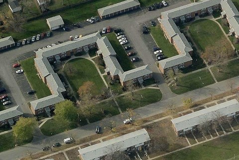 A parking lot is surrounded by a building with a grassy area in the middle.