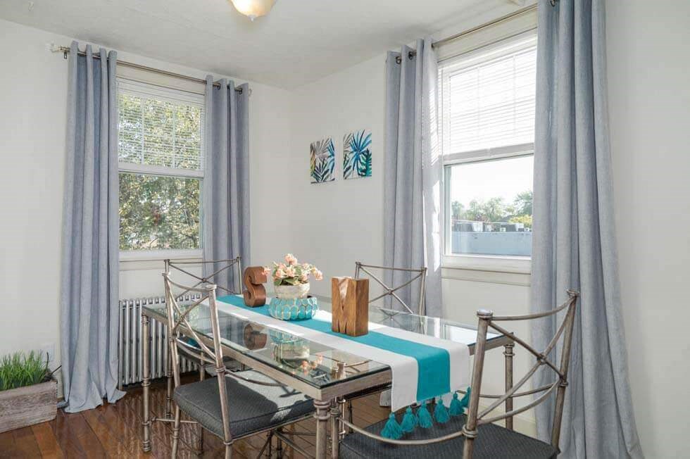 a dining room with a table and chairs and two windows