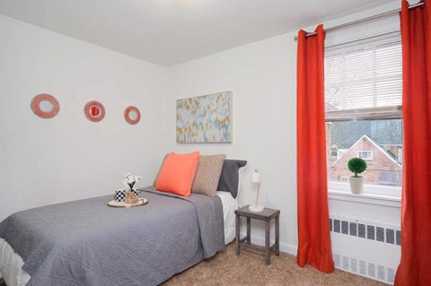 a bedroom with a bed and a window with orange curtains