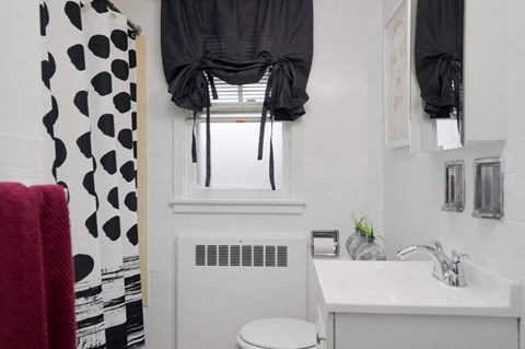 a white bathroom with a black and white shower curtain and a window