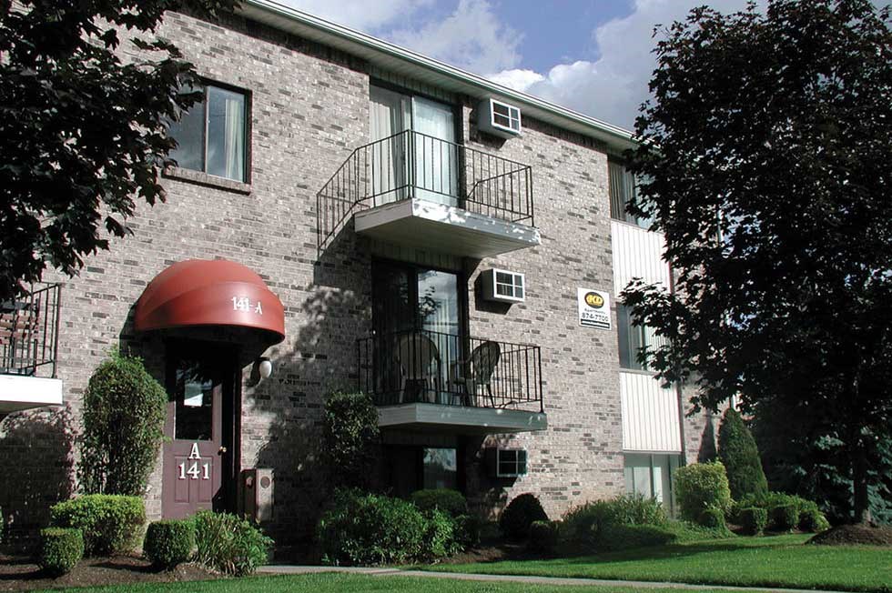 a brick apartment building with a balcony and a red umbrella