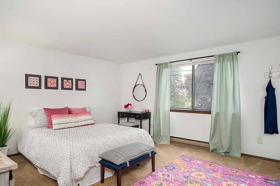 a white bedroom with a bed and a window