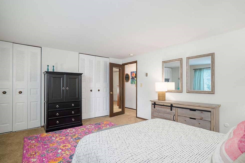 a bedroom with a bed and a dresser and two mirrors