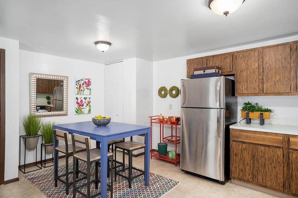 a kitchen with a blue table and a stainless steel refrigerator