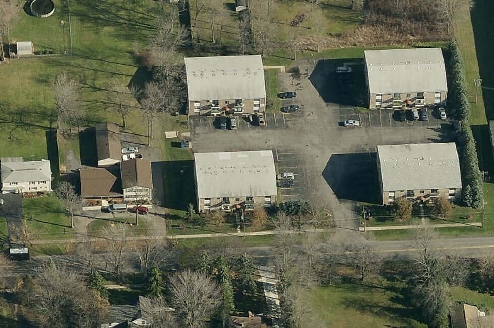 an aerial view of several buildings and cars in a field